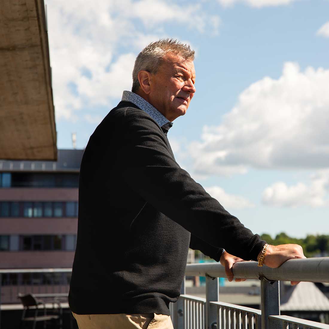 Veidekke employee standing outside on a veranda looking at the view of the urban environment