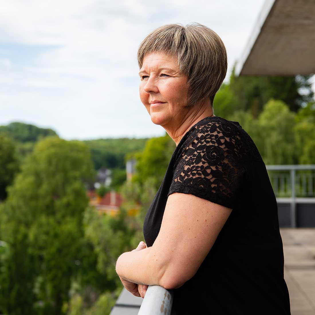 Veidekke employee standing outside on a veranda looking at the view of the urban environment